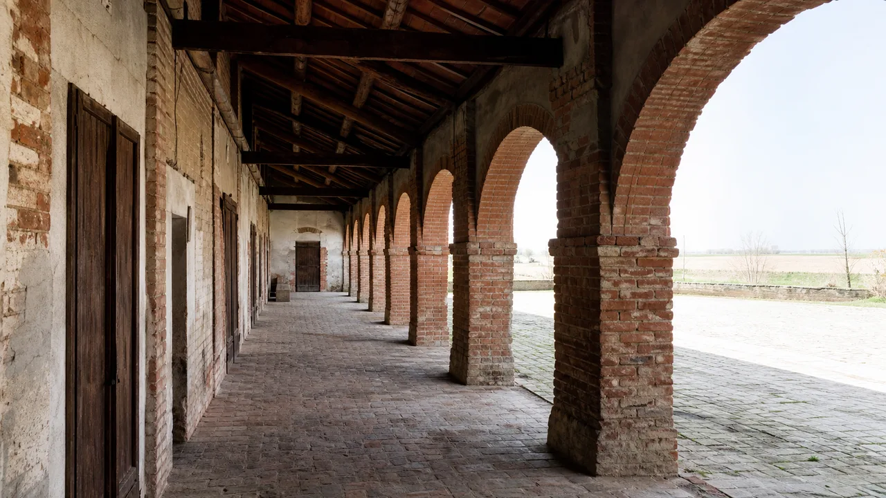 Portico ad archi in mattoni di una cascina lombarda affacciato sulla corte
